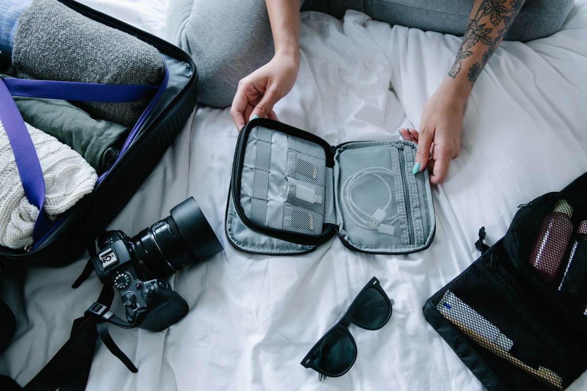 Traveler holding a zipped organizer among travel essentials