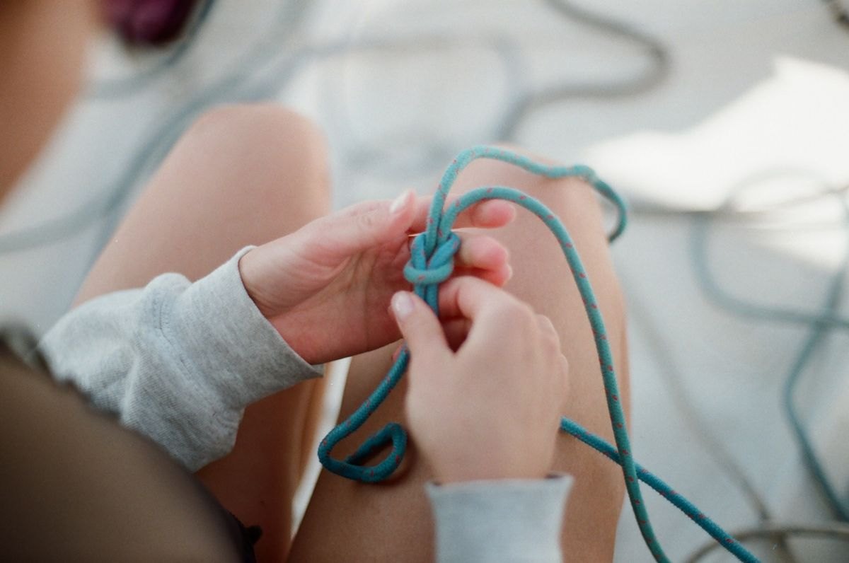 Hands tying a knot in a length of blue rope