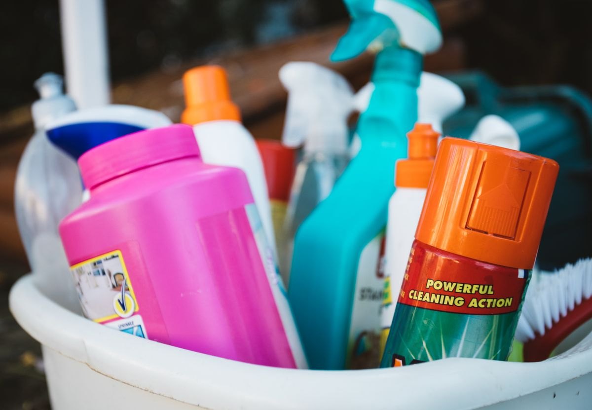 Household cleaning products stored together in a bucket